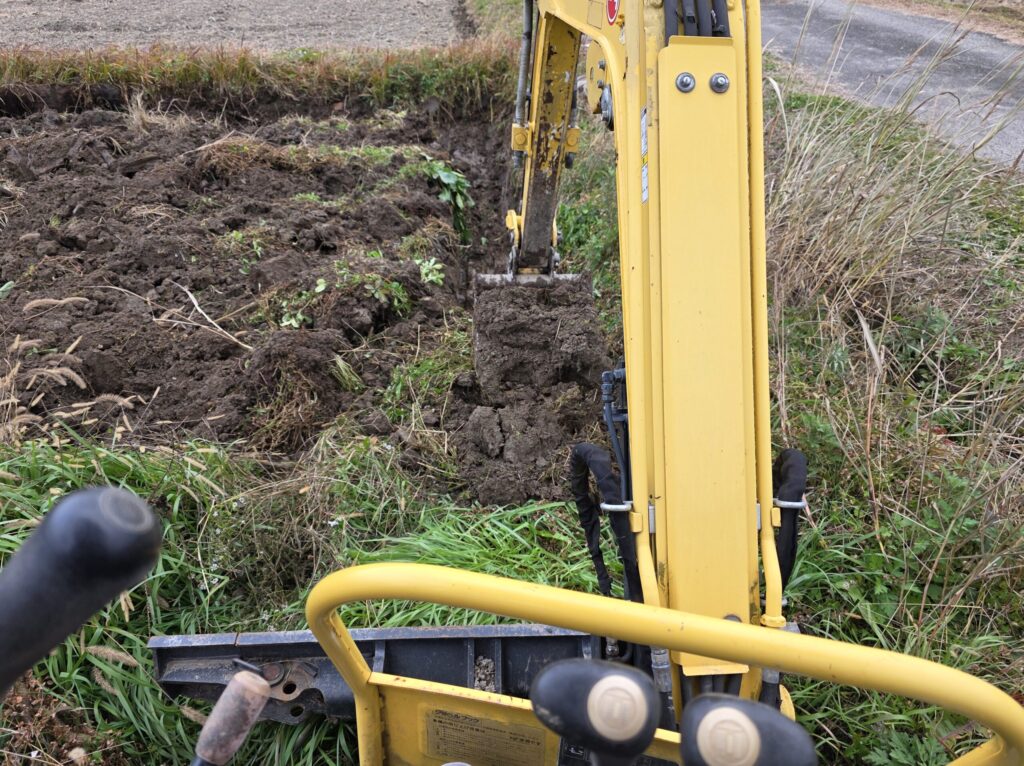 南丹市八木町の八木ファームにて油圧ショベルで排水溝を掘る様子
