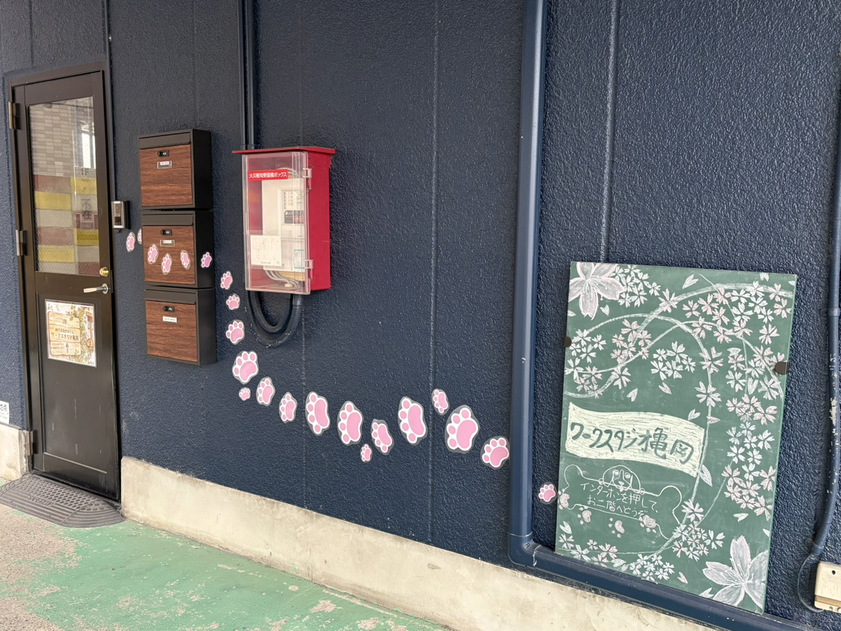 入り口ドアへと誘導する壁のピンク色の肉球ステッカー