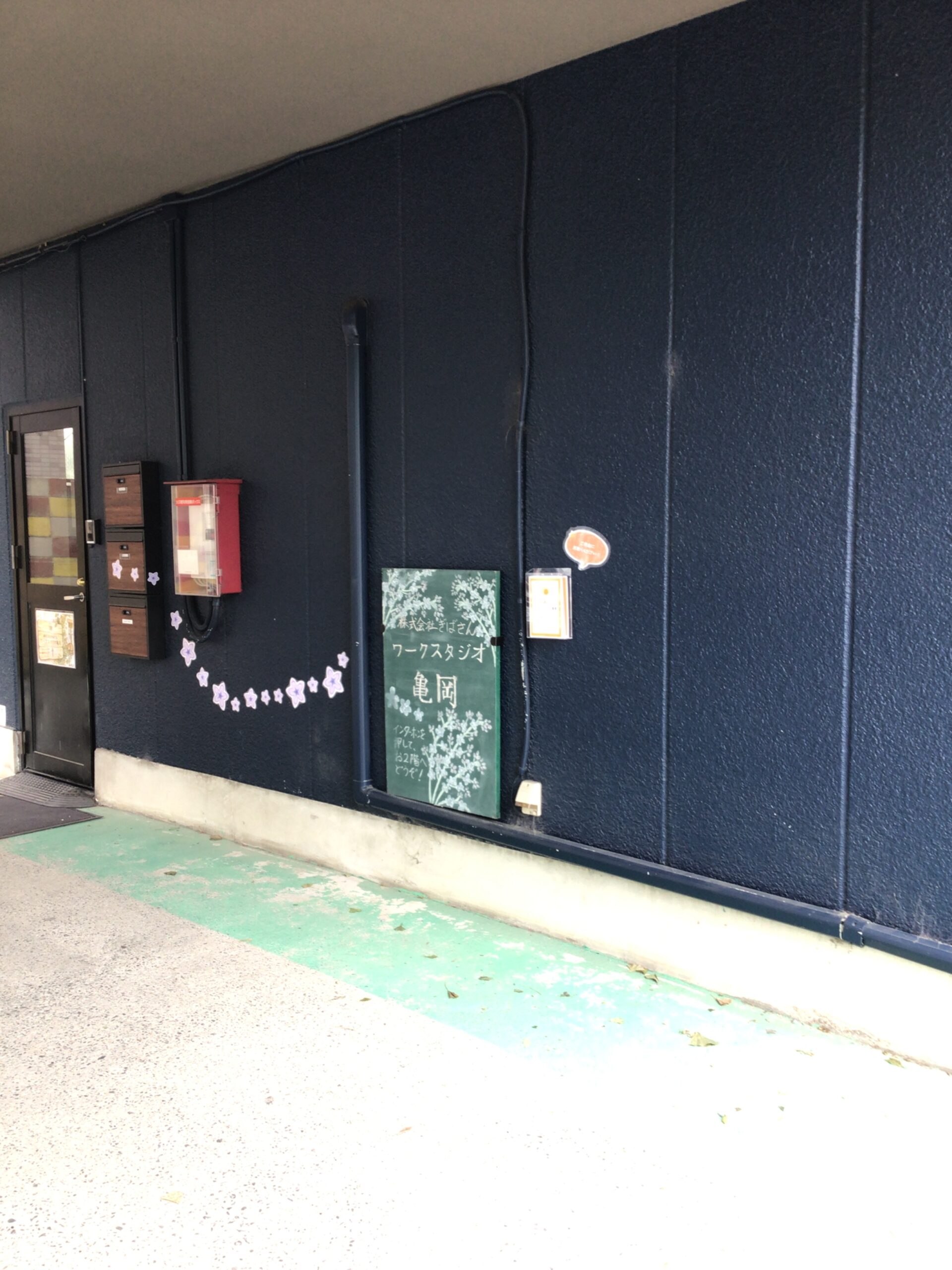 ワークスタジオ亀岡の入り口付近と緑の案内看板
