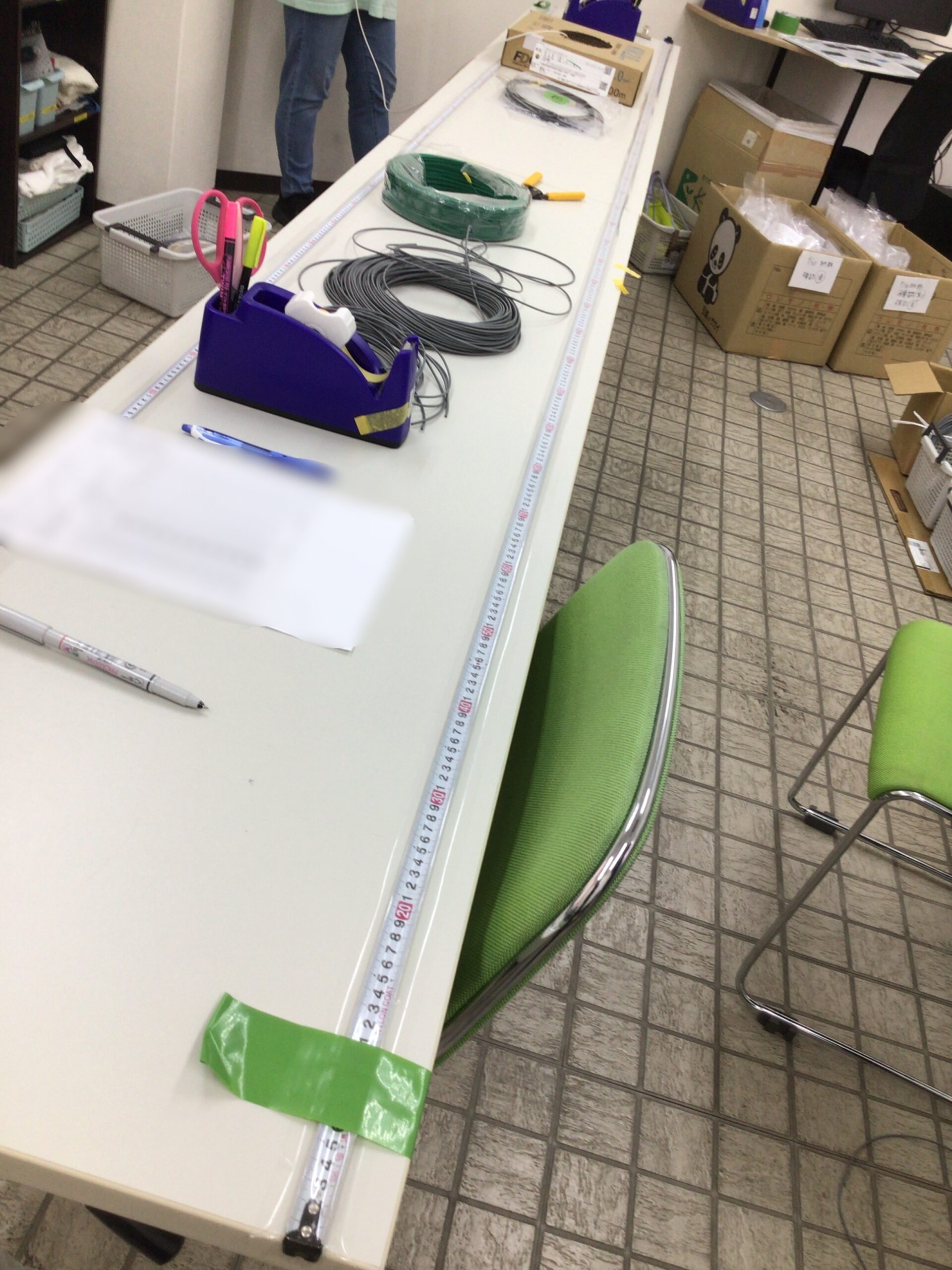 作業机に直接固定された長いメジャーでケーブルの長さを正確に測る工夫